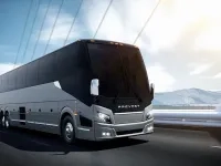 Autocar Prevost roulant sur une route, avec des montagnes en arrière-plan.